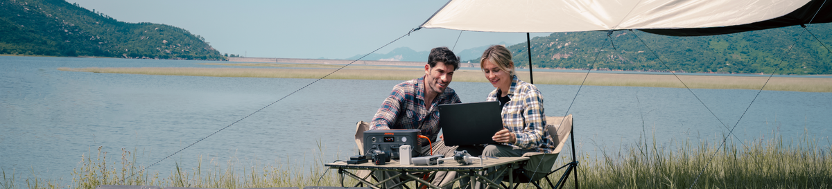 A couple using a Jackery power station beside a lake